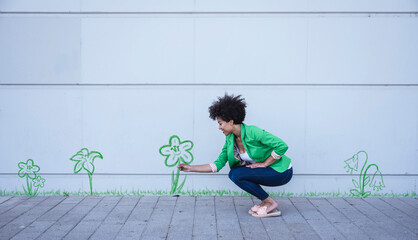 Crouching woman plucking painted flower from wall