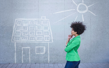 Young woman looking at painted house with solar panels on wall