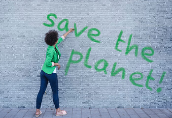 Young woman writing Save the Planet on wall