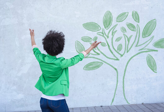 Woman presenting painted tree on wall