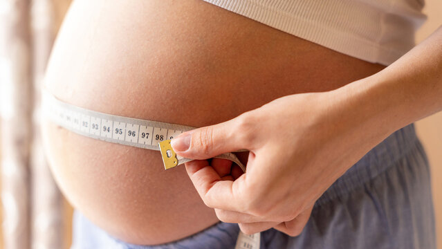 Pregnant belly woman measure. Happy beautiful pregnant woman with tape measuring belly. Pregnancy, medicine health care concept.