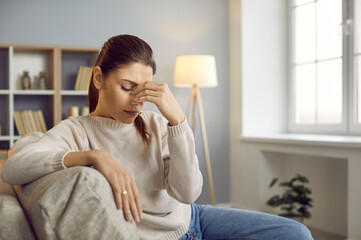 Stressed young Caucasian woman massage eyes suffer from headache or migraine at home. Unhealthy...