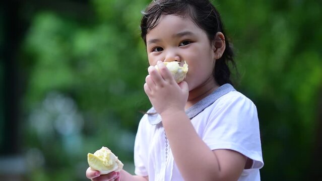 Girl eating durian with happy face. Tropical seasonal fruit, king of fruit from Thailand.