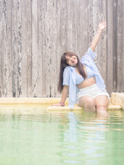 Chubby happy young asian woman dressed in swimsuit near swimming pool.