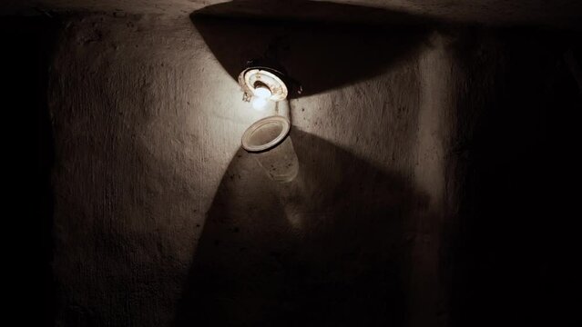 Dark gloomy basement with a luminous light bulb in a disassembled glass ceiling