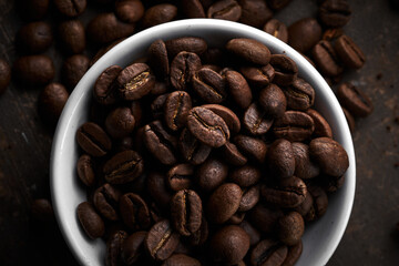 Naklejka premium Roasted coffee beans in bowl isolated close up on brown grunge background