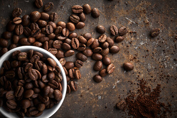 Obraz premium Roasted coffee beans in bowl isolated close up on brown grunge background