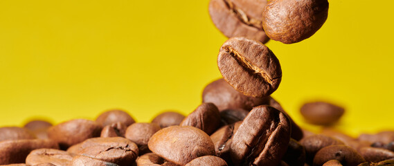 Roasted coffee beans isolated close up on yellow background, clipping path