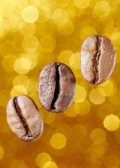 Roasted coffee beans isolated close up on gold glitter background, clipping path