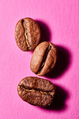 Obraz premium Roasted coffee beans isolated close up on pink background, clipping path