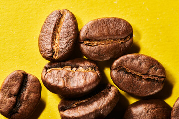 Roasted coffee beans isolated close up on yellow background, clipping path