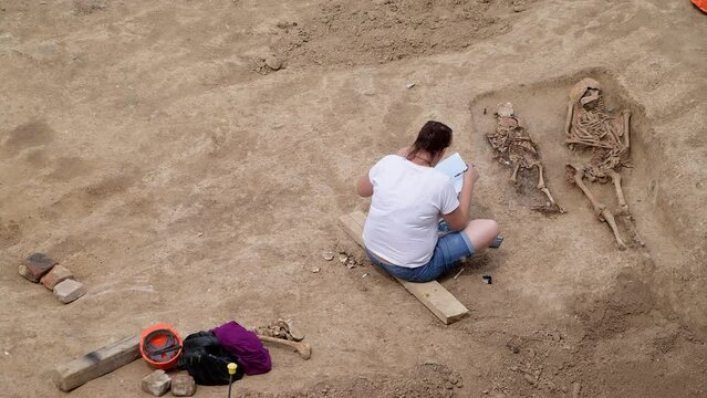 Young archeologist works on an archaeological site at morning sun rays at summer heat