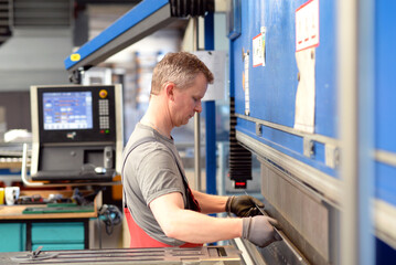 employee operates bending machine in a metalworking company - bending of sheet metal for further...
