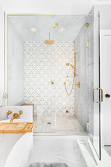A beautiful tiled shower and tub with gold and white tiles on the walls, mosaic marble tiles on the...