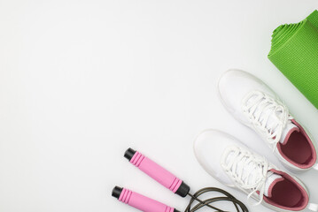 Active lifestyle concept. Top view photo of white sneakers green sports mat and skipping rope on isolated white background with copyspace