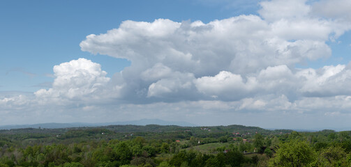 Huge cumulonimbus cloud above hilly countryside, weather change