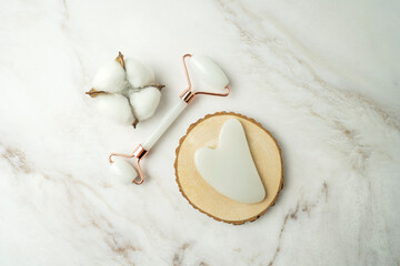A quartz roller for face massage and gua sha for antiaging procedures in the form of the heart lying on a table