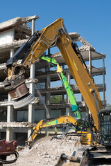 Fototapeta na wymiar heavy duty Excavators demolishing an old commercial business house building