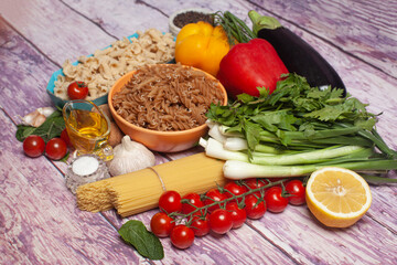 Italian pasta with vegetables, olive oil, spices on a wooden background