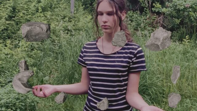 Girl using telekinesis, brain force or magic to levitate stones. Loop.