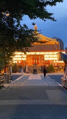 The path to the beautiful Japanese temple at night with Japanese paper lanterns lit in gold, the dim reflects on the exterior of the temple building, heartwarming scenery of the cultural scene Tokyo, 