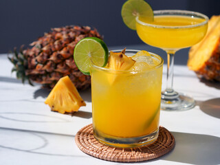 Summer cocktail glass with fresh pineapple and lime, direct sunlight shooting