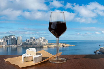 Glass of red wine with cheese with view of Sliema town and harbor. Photo taken from  Valletta, Malta.
