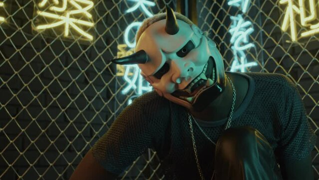 Low angle of young Black man with white hair in mask of demon sitting in studio with netting fence and neon lights meaning nirvana and western paradise