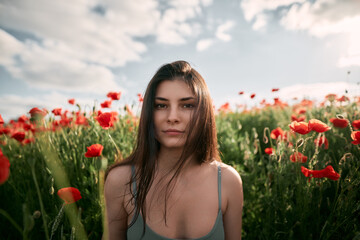 Naklejka premium Young girl in the poppy field. Woman in the coutryside at the summer