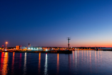 Fototapeta na wymiar Wieczór w porcie rybackim. Oświetlona przystań dla kutrów, łodzi oraz jachtów.