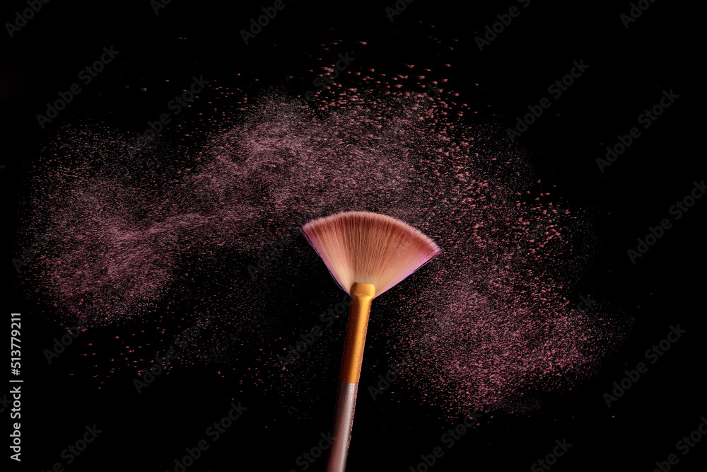 Wall mural Make up brush with cosmetic powder splash, over black background. Splash image