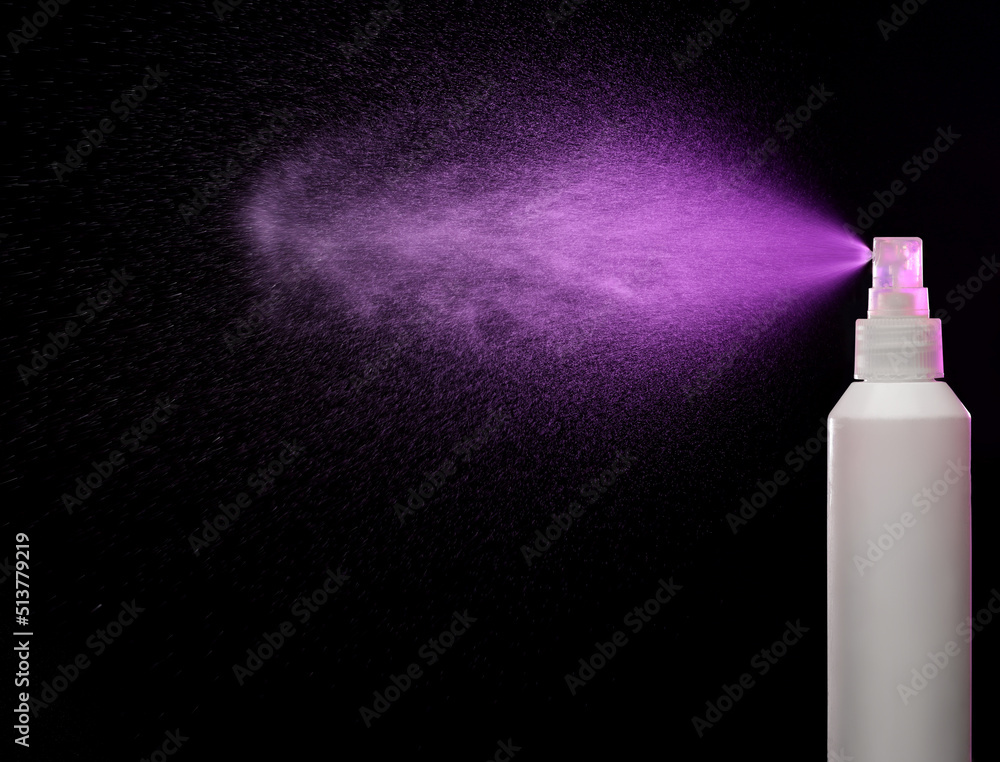 Wall mural spraying product in spray bottle over black background