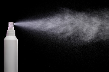 Spraying product in spray bottle over black background