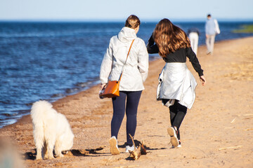 Mom with daughter and dog walking on the beach on a cool day