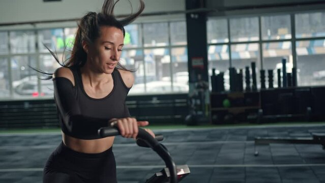 Young female athlete trains cardio on a bicycle with a fan, cardio and endurance training