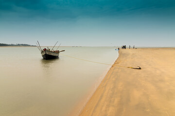 Moody image of a boat on water tied by a rope with an anchor on river bed at Tajpur, West Bengal,...