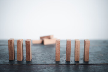 Businessman hand protecting wooden domino concept of business risk planning Fight goals for success
