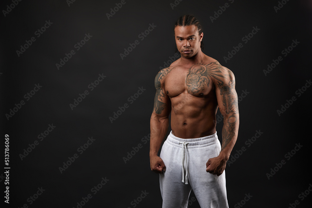 Wall mural Handsome shirtless muscular black young man, looking at camera, on dark background in studio shot