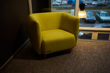 Modern comfortable yellow armchair in the furniture store hallway against large windows backdrop, displayed for sale. Office and Home interior design