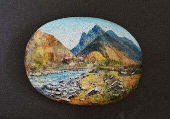 A mountain landscape painted on stone and lying on a dark slate.
