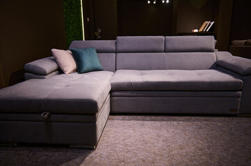 Modern comfy soft upholstered purple sofa with green and beige pillows in the exhibition hall of furniture shop