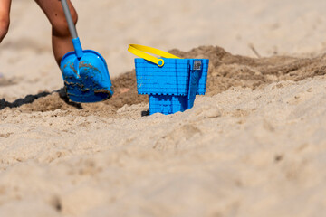 niebieskie wiaderko na piasku plaży nad morzem w słońcu - obrazy, fototapety, plakaty
