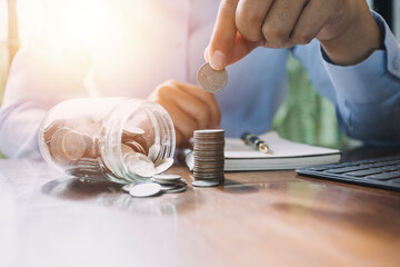 businessman holding coins putting in glass. concept saving money for finance accounting