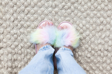 Woman's feet with a pink pedicure in colorful rainbow slippers