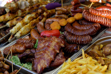 Grilled sausage with the addition of herbs and vegetables on the grill plate, outdoors. Grilling food, bbq, barbecue