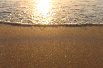 Sea waves and warm sunset light, calm and relaxing sandy beach