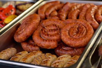 Grilled sausage with the addition of herbs and vegetables on the grill plate, outdoors. Grilling food, bbq, barbecue