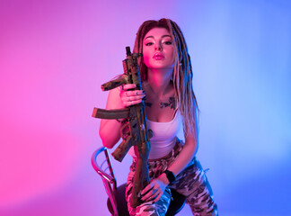 a cheeky girl with braided dreadlocks on her head in neon light with an automatic rifle