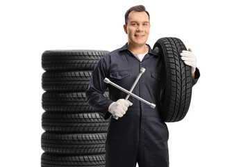 Auto mechanic with a tire and a wrench tool in front of a pile of tires - Powered by Adobe