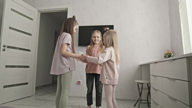 Smiling little girls playing funny game together, clapping hands, cute siblings having fun. Kids enjoying leisure time together. Joyful little sibling sister smiling and clapping their hands during